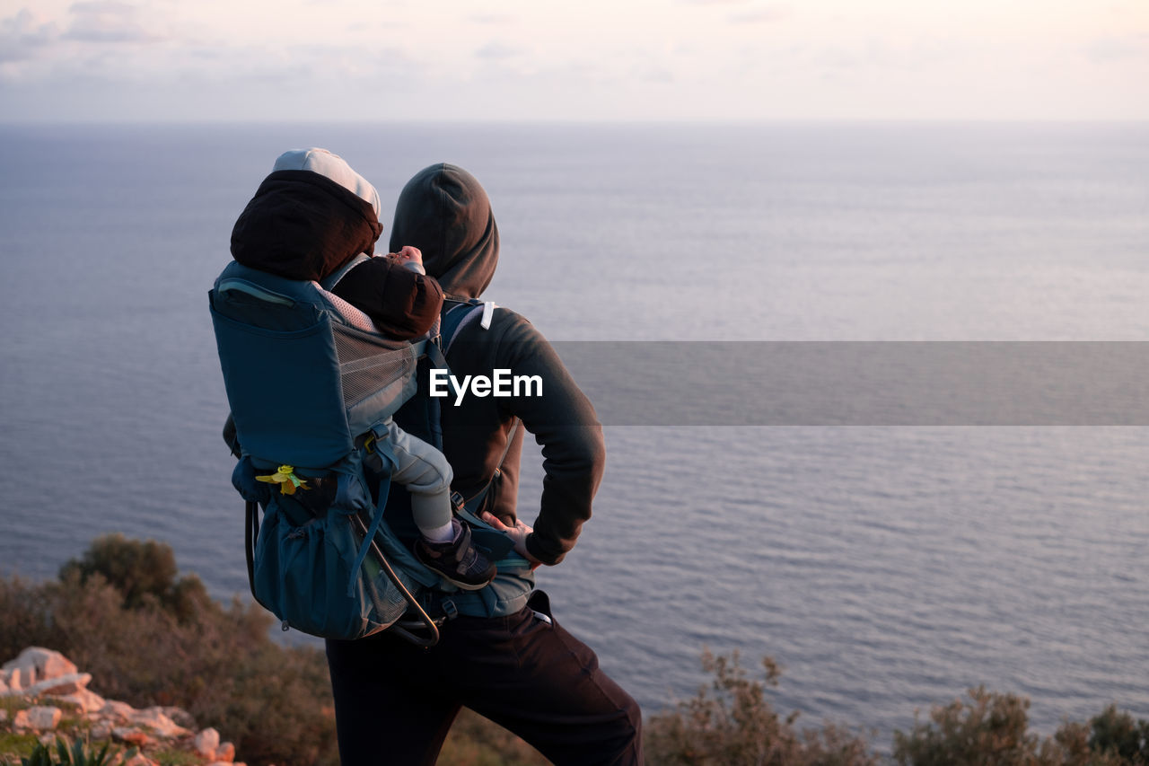 Rear view of woman photographing sea against sky