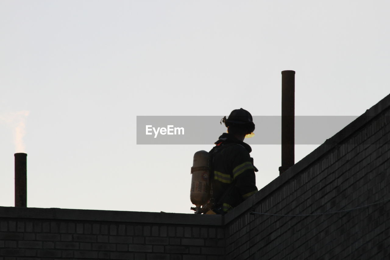 Low angle view of firefighter against clear sky