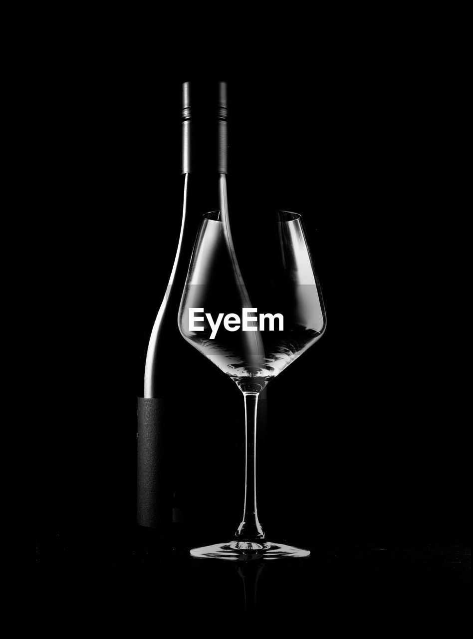 Close-up of wine glass and bottle on table against black background