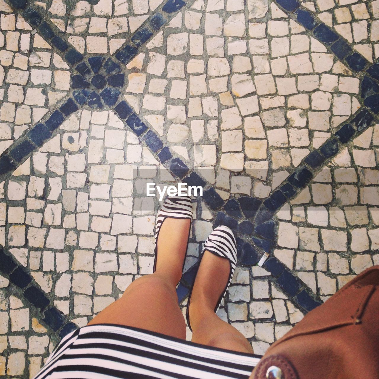 LOW SECTION OF WOMAN STANDING ON ZEBRA CROSSING