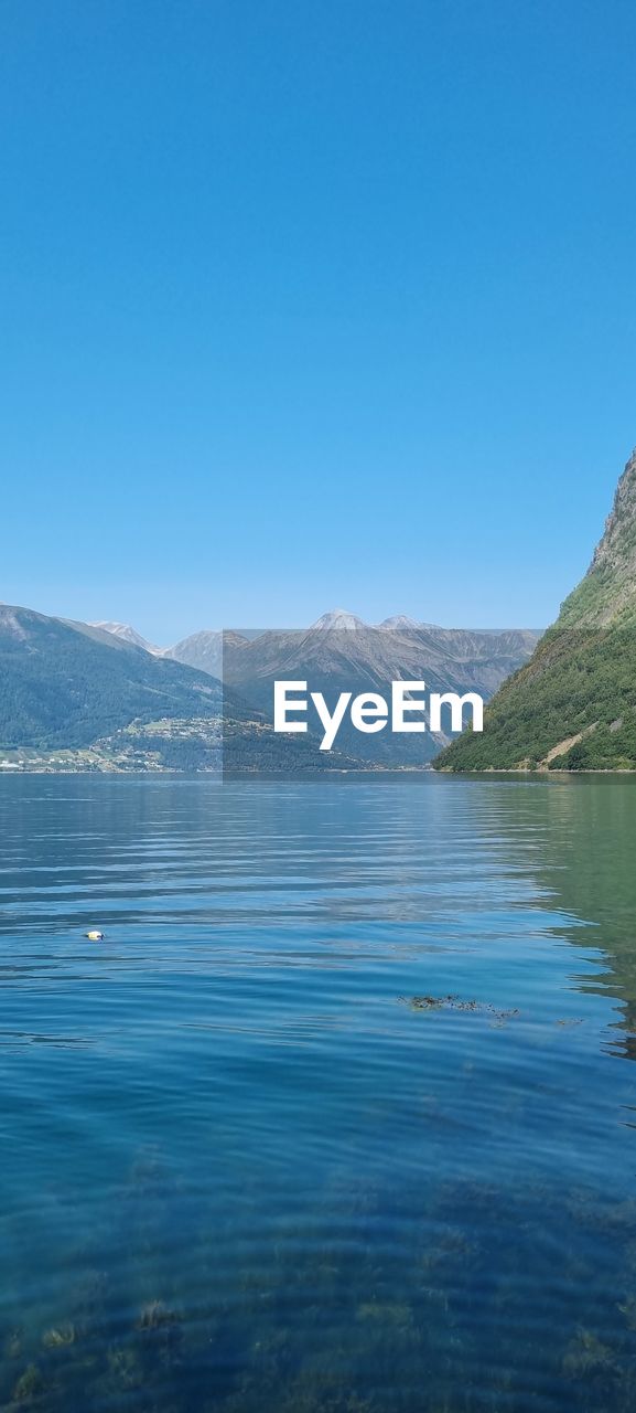 SCENIC VIEW OF LAKE AND MOUNTAINS AGAINST BLUE SKY