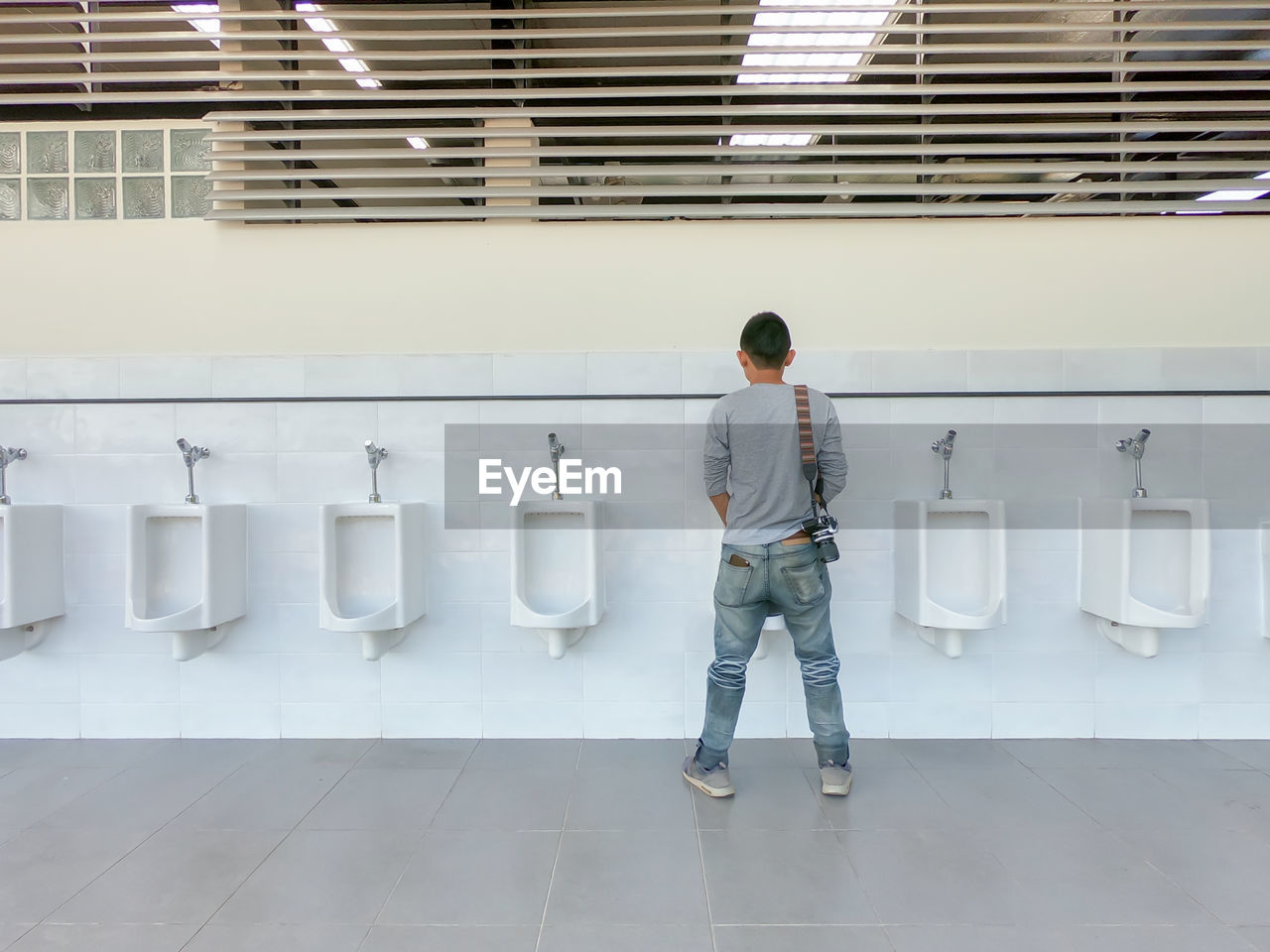 Rear view of man standing at public urinal