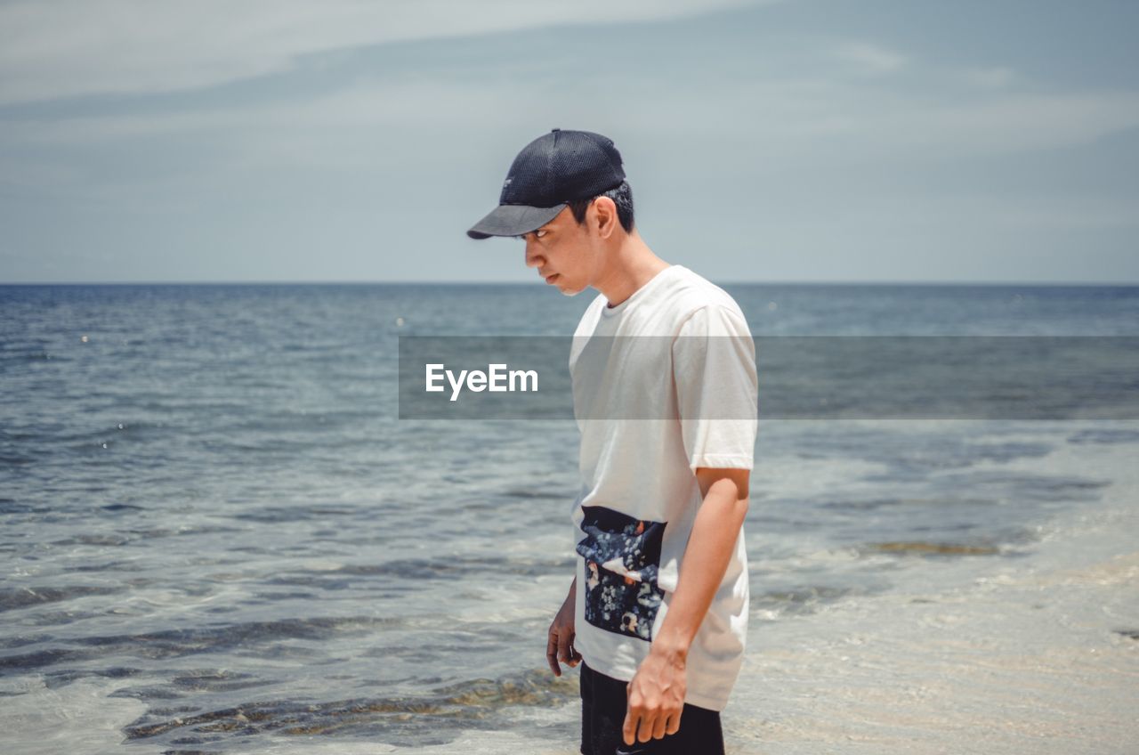 Man standing at beach against sky