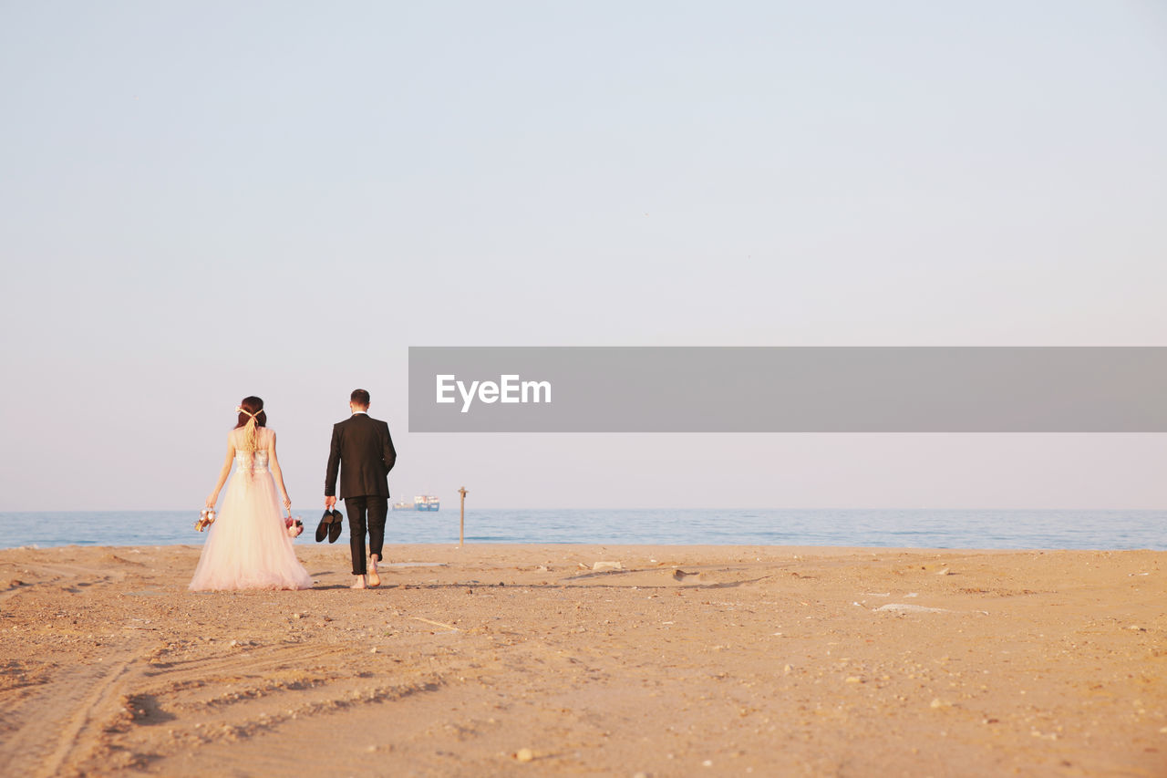 Rear view of bride and groom on beach