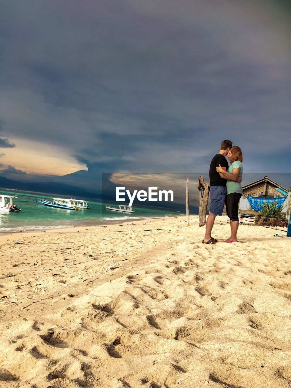 Full length of couple embracing at beach against sky