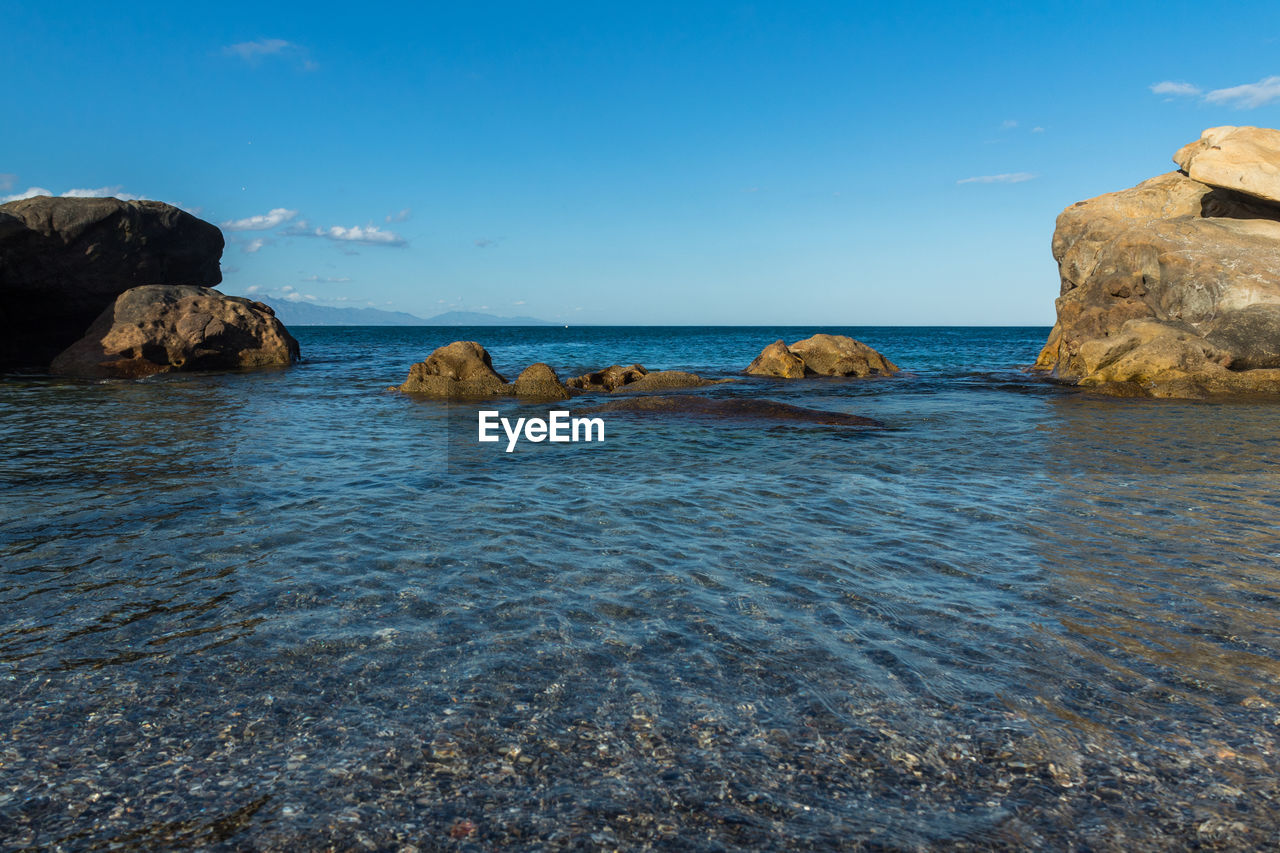 Rocks in sea against blue sky