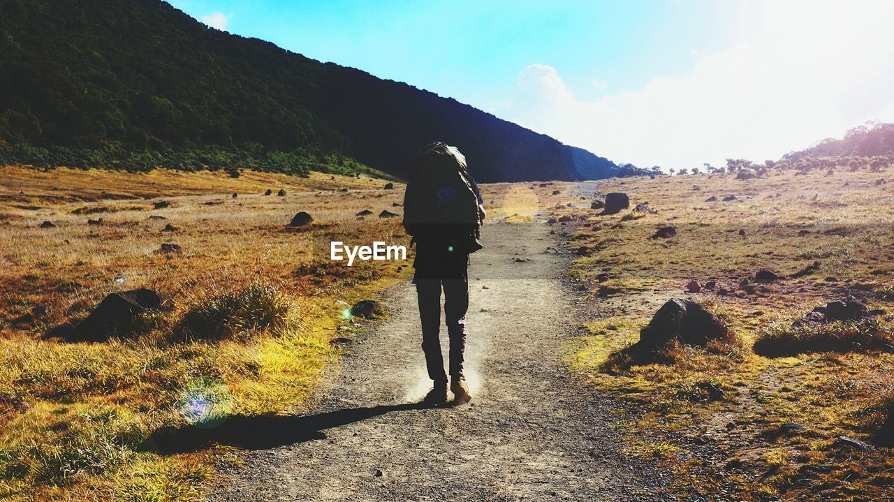 FULL LENGTH OF MAN STANDING ON MOUNTAIN ROAD