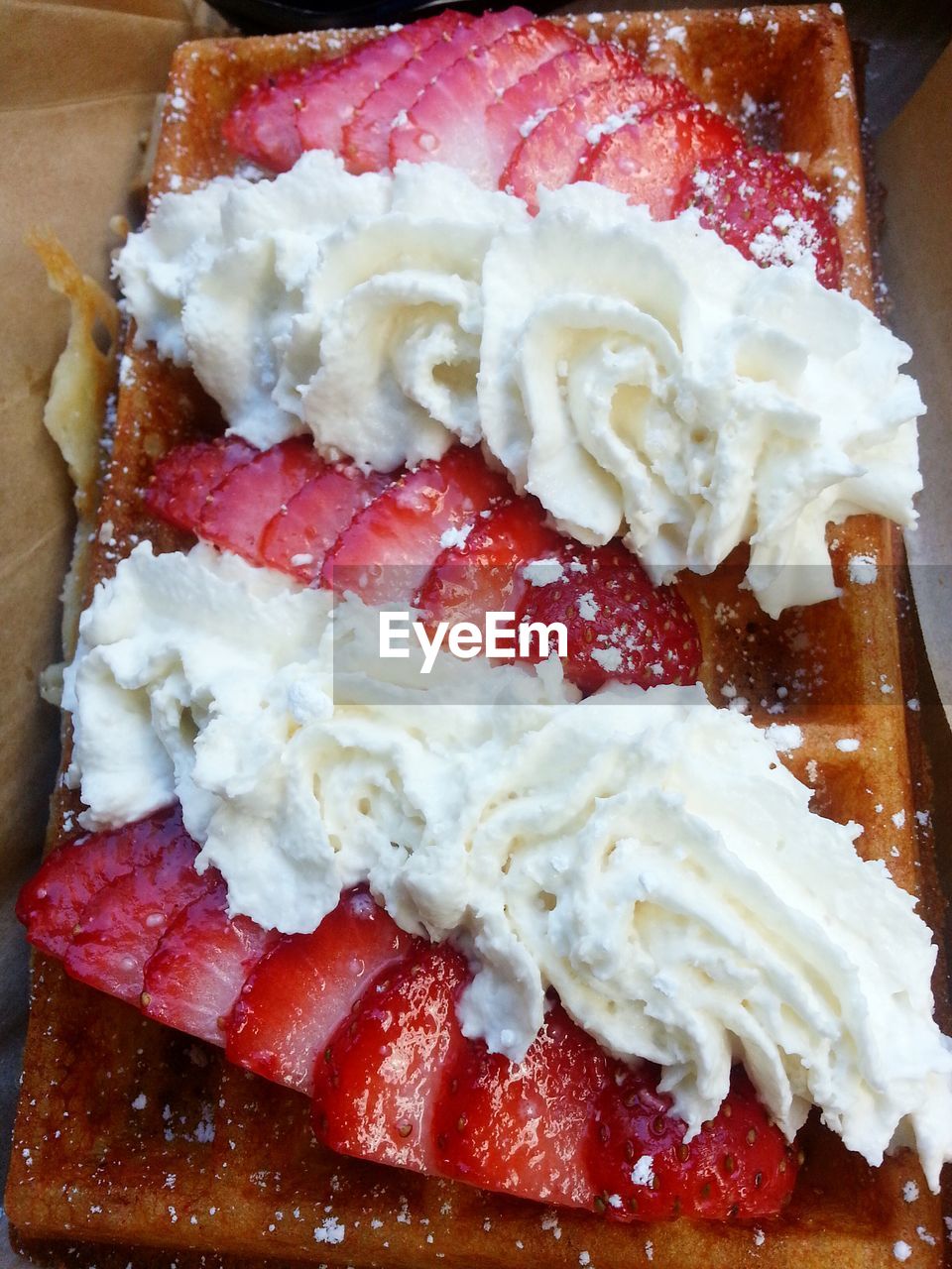 Close-up of cream with sliced strawberries on waffle