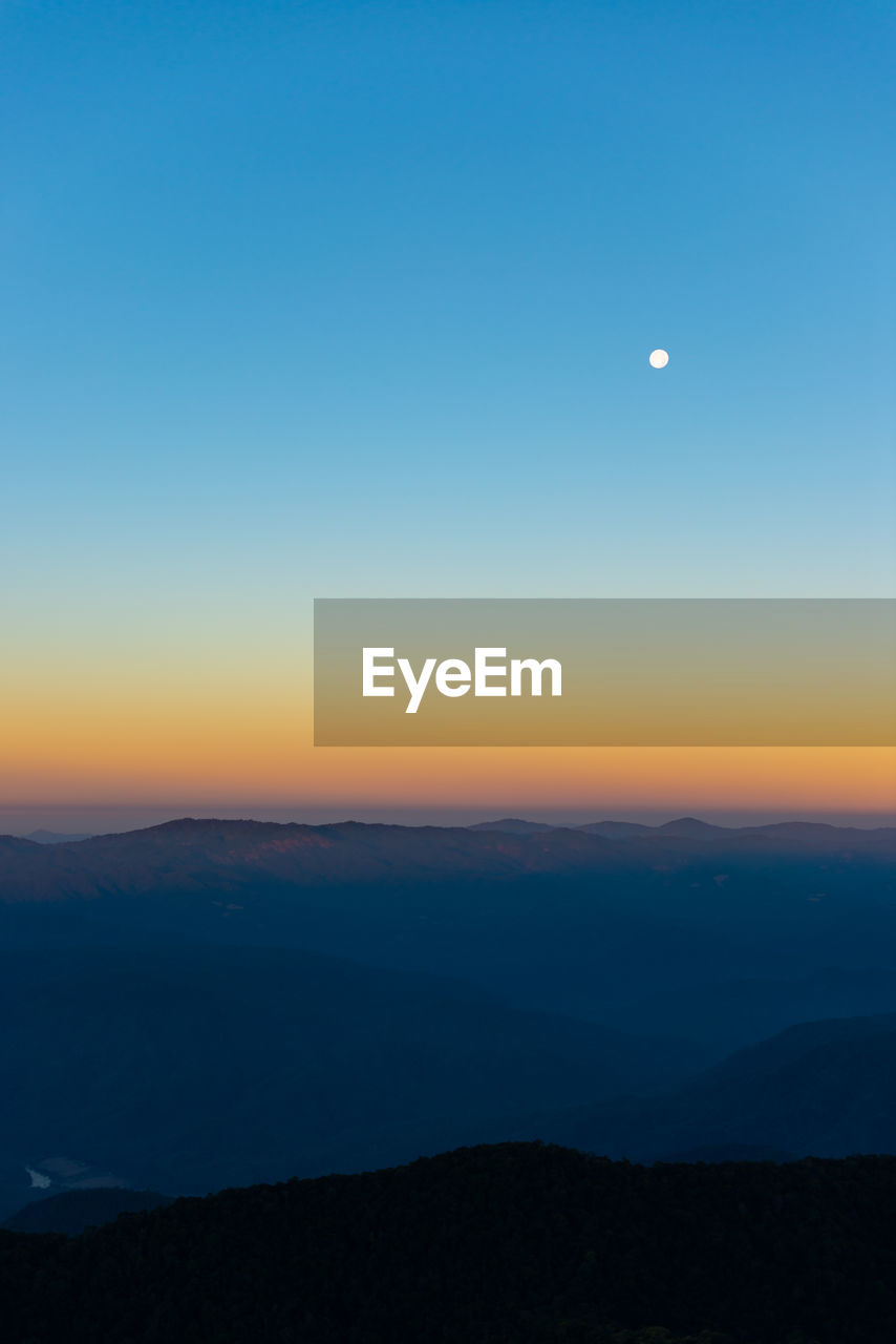 Scenic view of silhouette mountains against clear sky during sunset