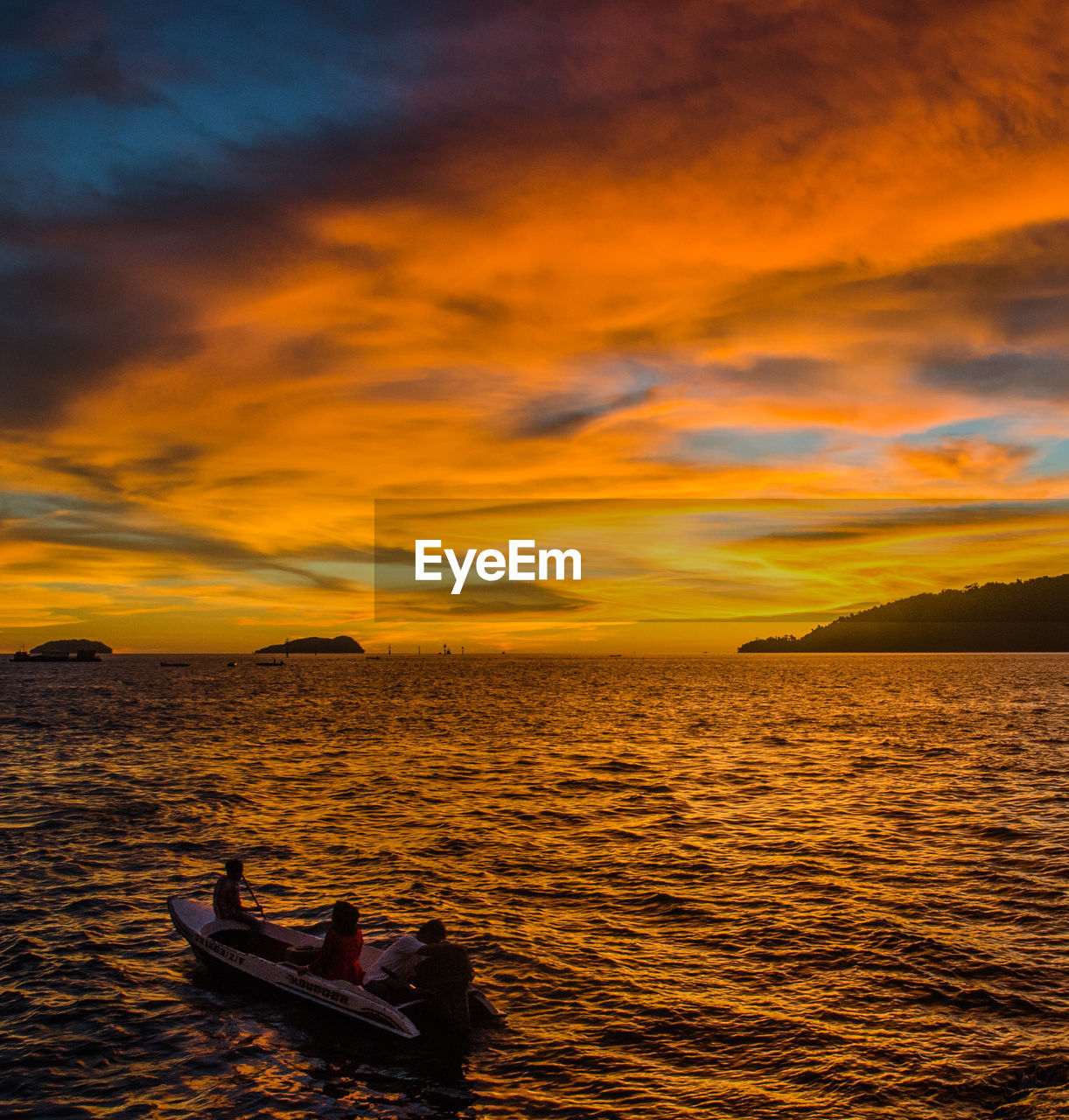 SILHOUETTE MAN ON BOAT IN SEA AGAINST ORANGE SKY