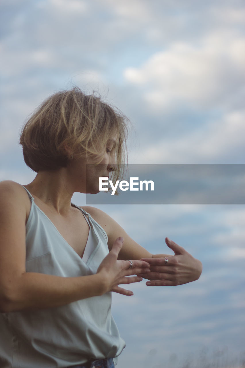 Beautiful woman dancing against cloudy sky