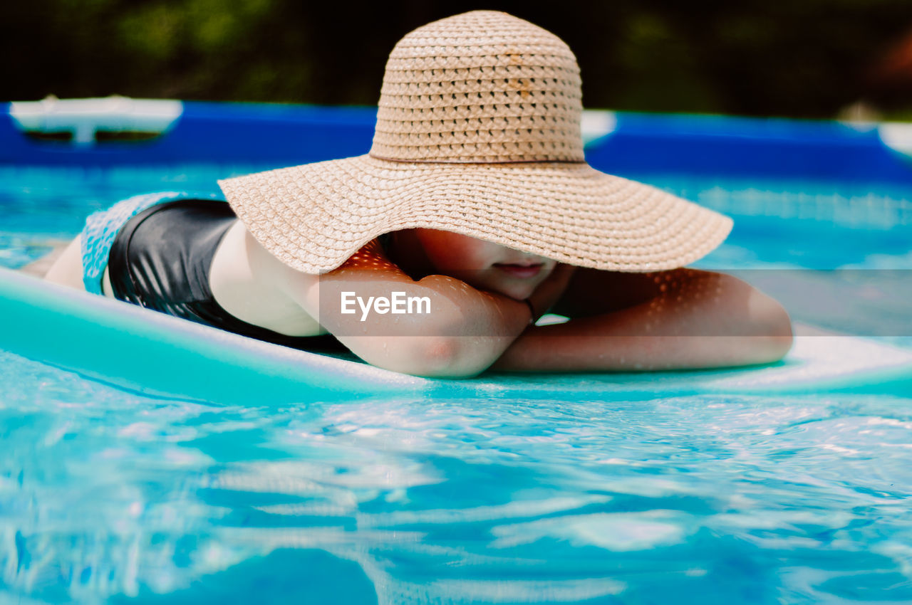 Girl lying on pool raft in swimming pool