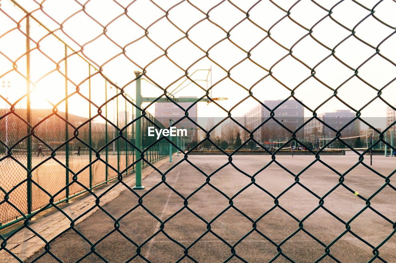 Basketball hoop seen through chainlink fence against sky