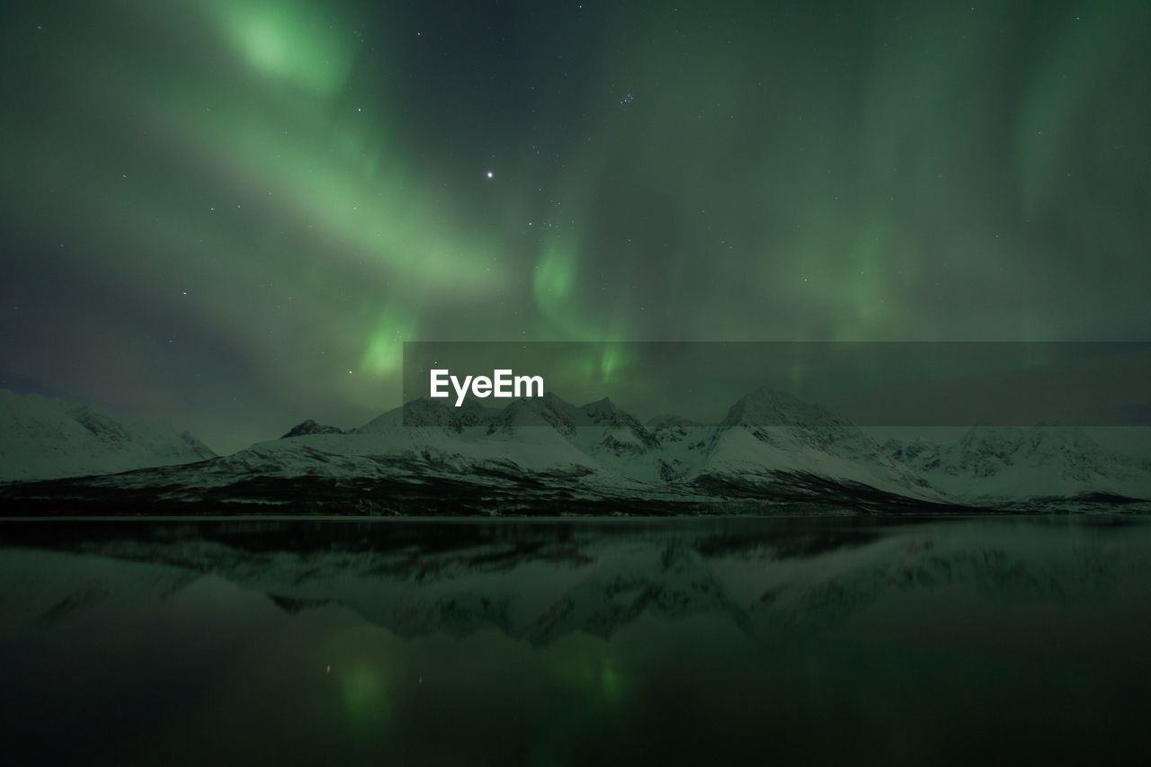 Scenic view of aurora borealis over lyngen alps and lake