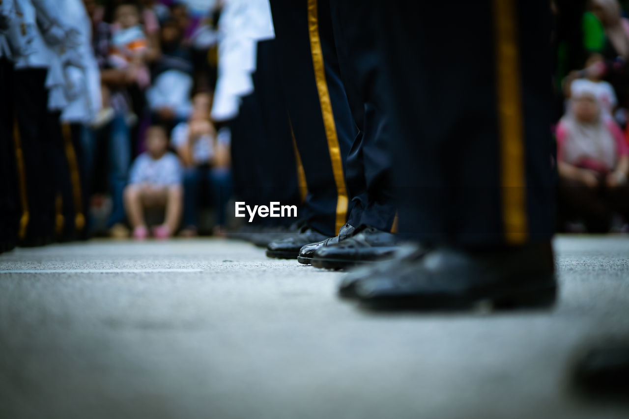 Low section of people standing on street wearing uniform