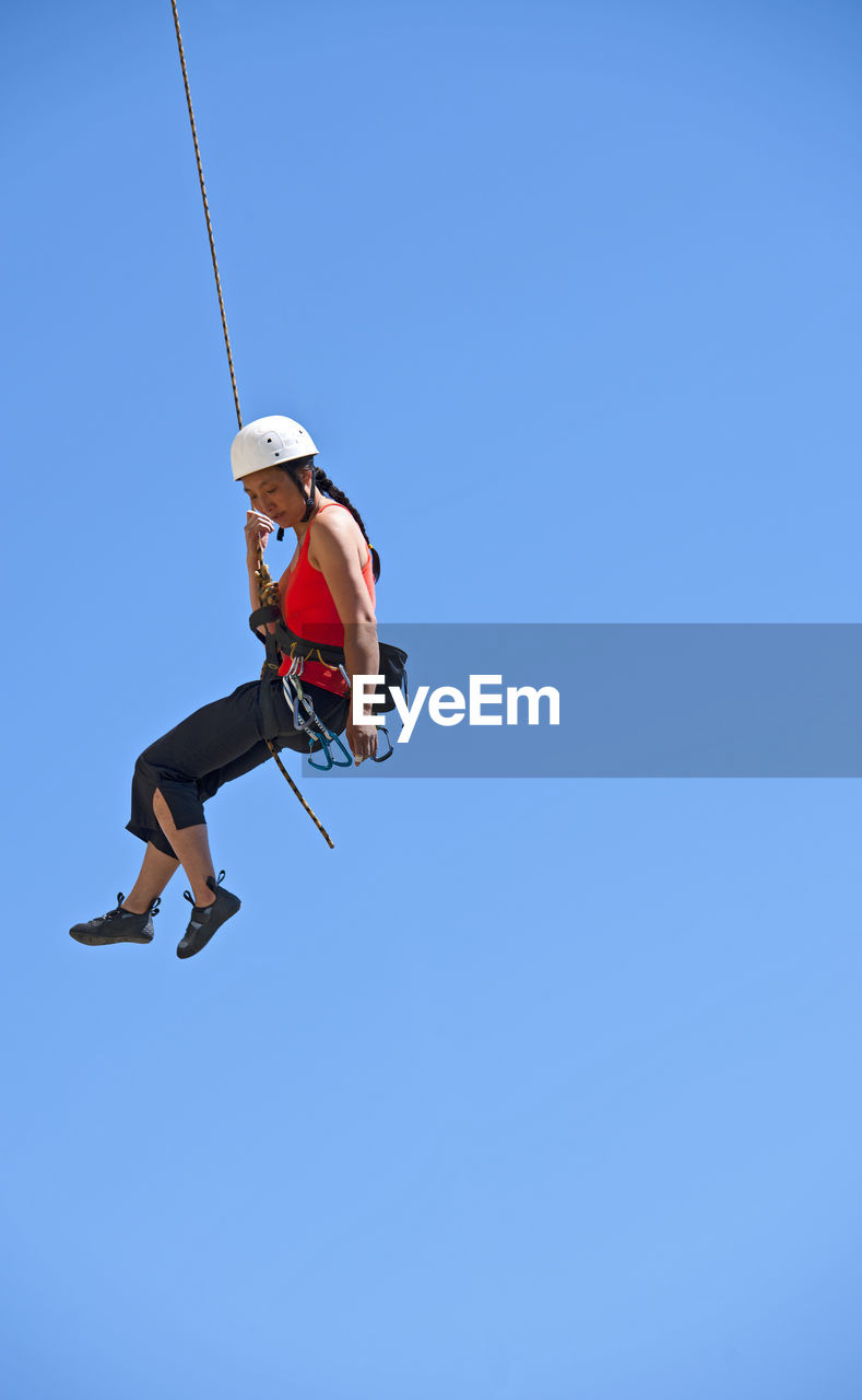 Woman rappelling from rock face in swanage / uk