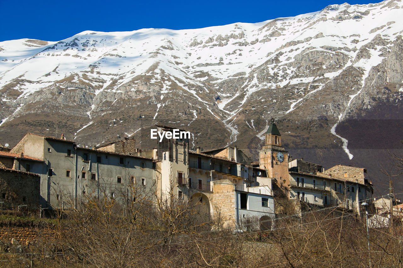 HOUSES AGAINST SNOWCAPPED MOUNTAINS AGAINST SKY