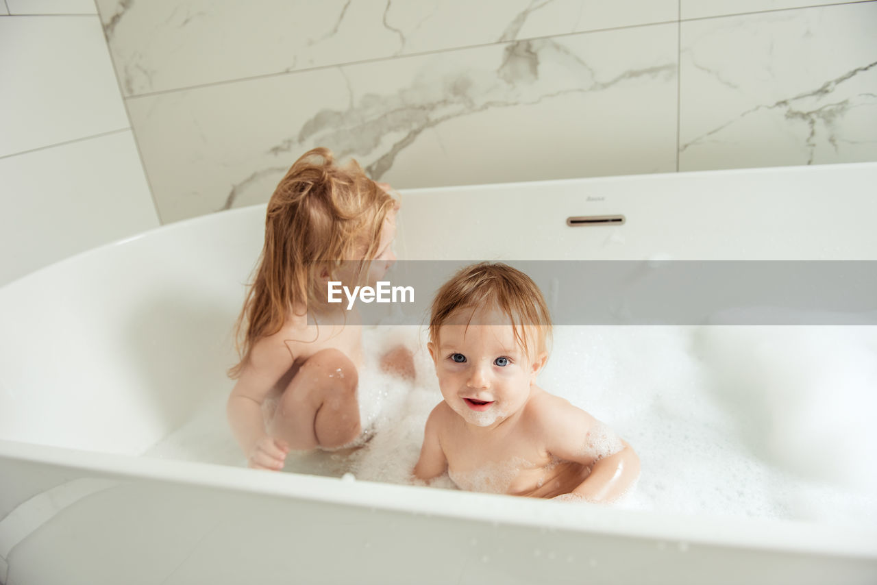 Little brother and sister bathing in a foam bath