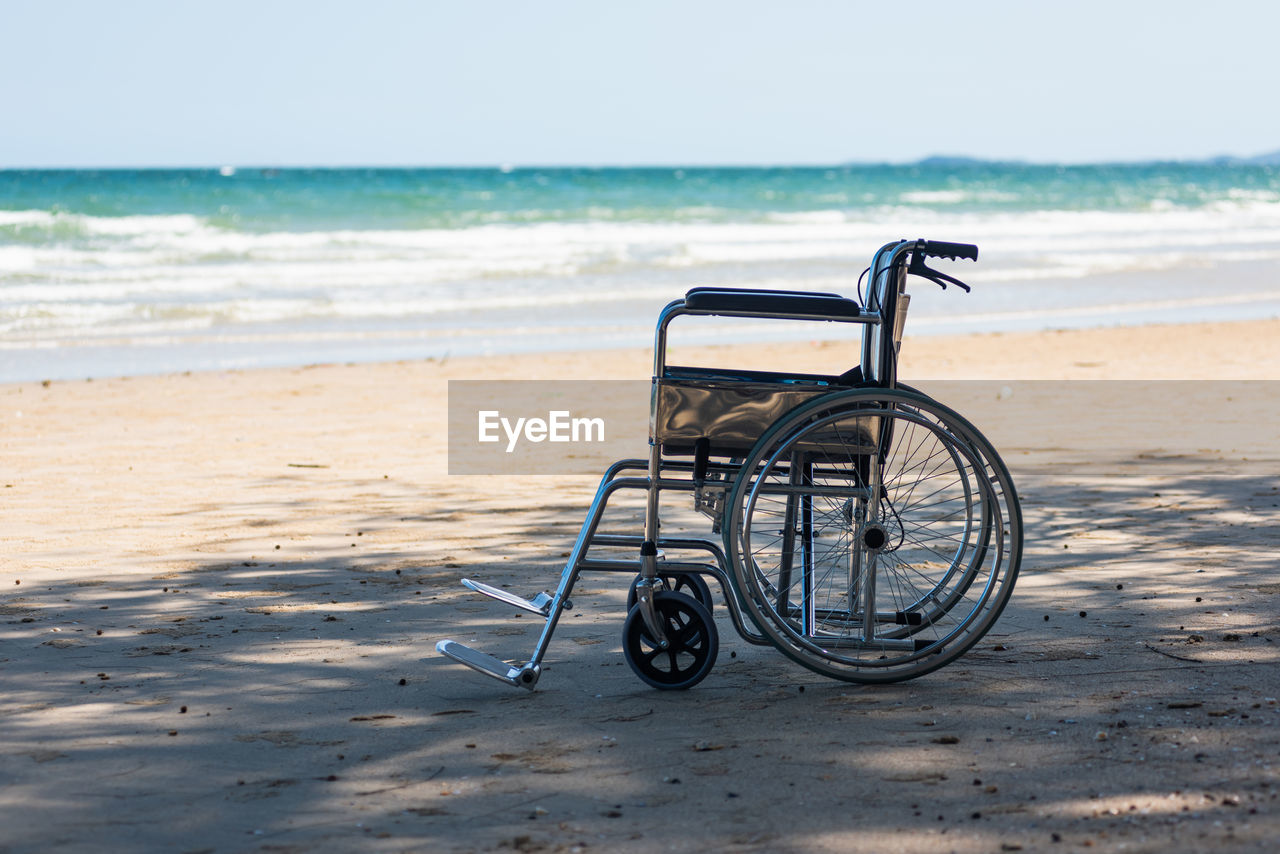 Empty nobody wheelchair on sand of the beach for taking the patient travel