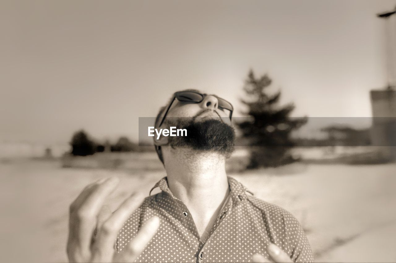 PORTRAIT OF YOUNG MAN LOOKING AWAY AGAINST SKY