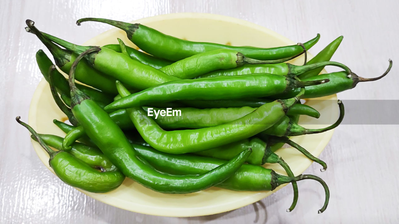 CLOSE-UP OF GREEN CHILI PEPPER ON TABLE