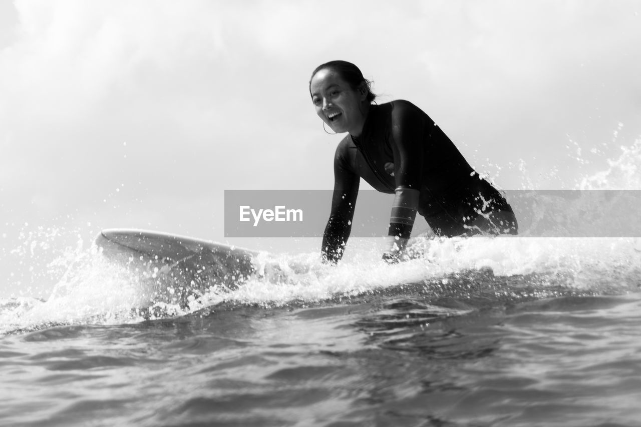 Side view of womamln sitting on a surfboard