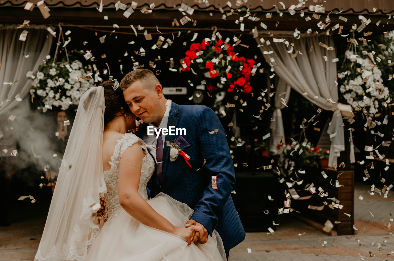 portrait of bride and bridegroom standing against building