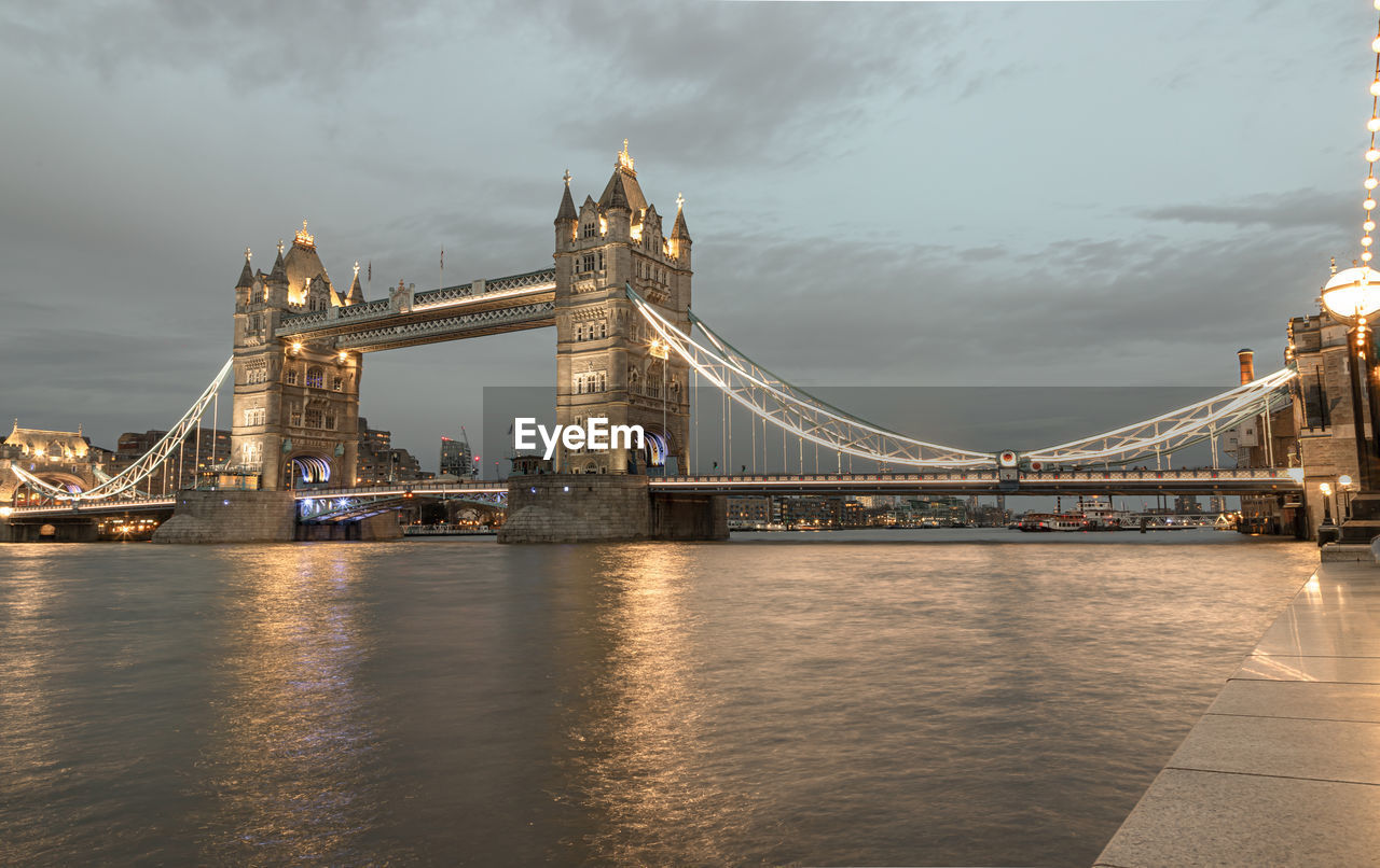 illuminated bridge over river in city at night