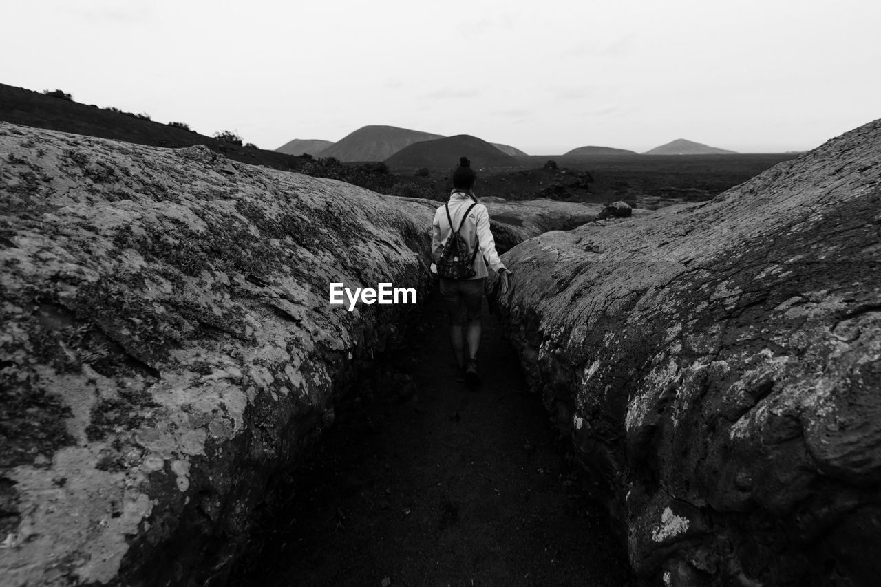 Rear view of woman standing on mountain against sky