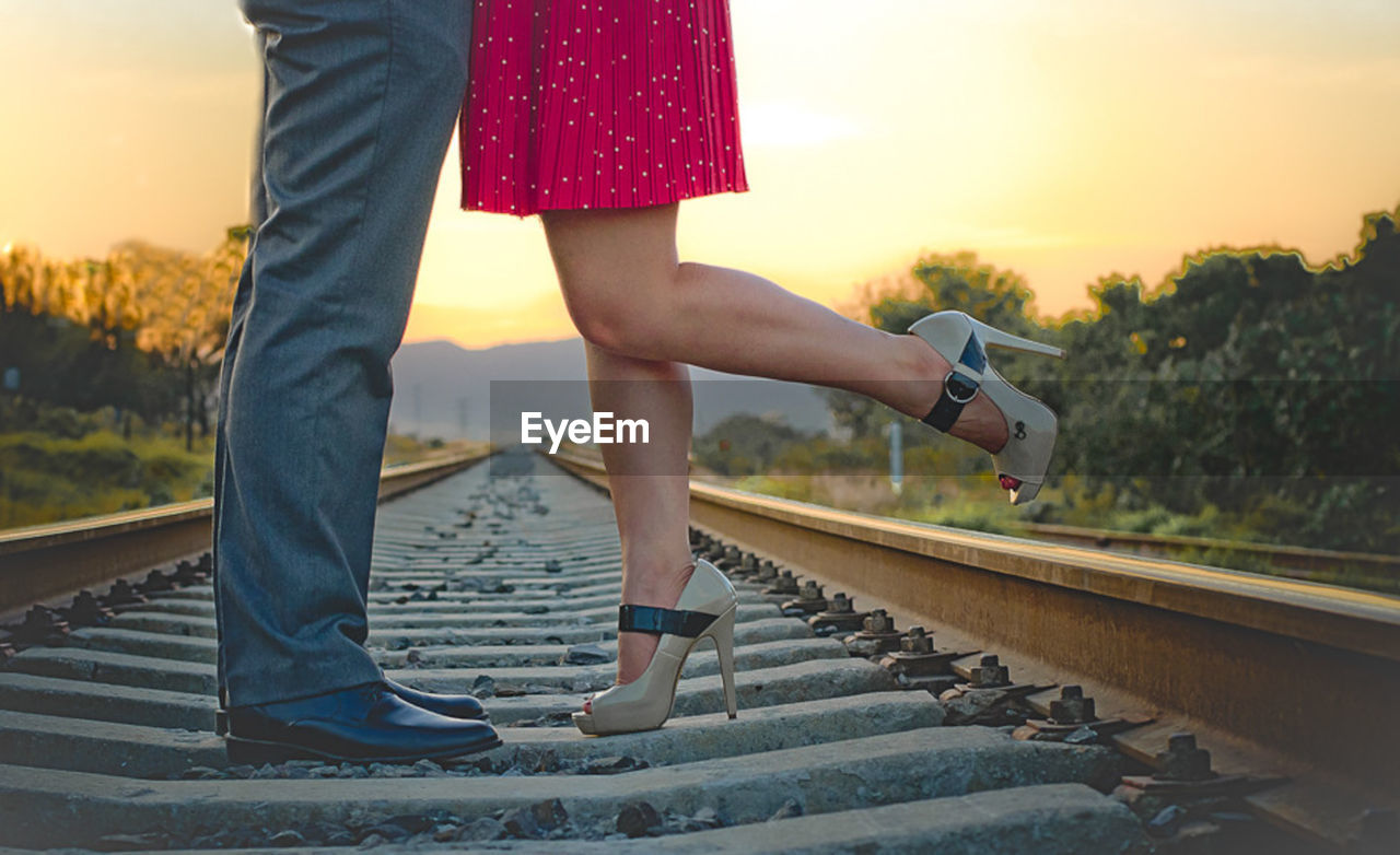 Low section of couple standing on railroad track