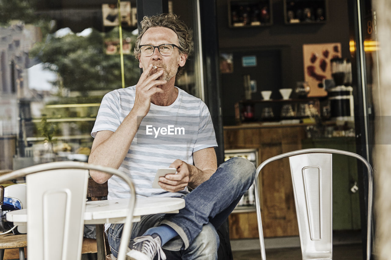 Smoking man sitting in front of a coffee shop