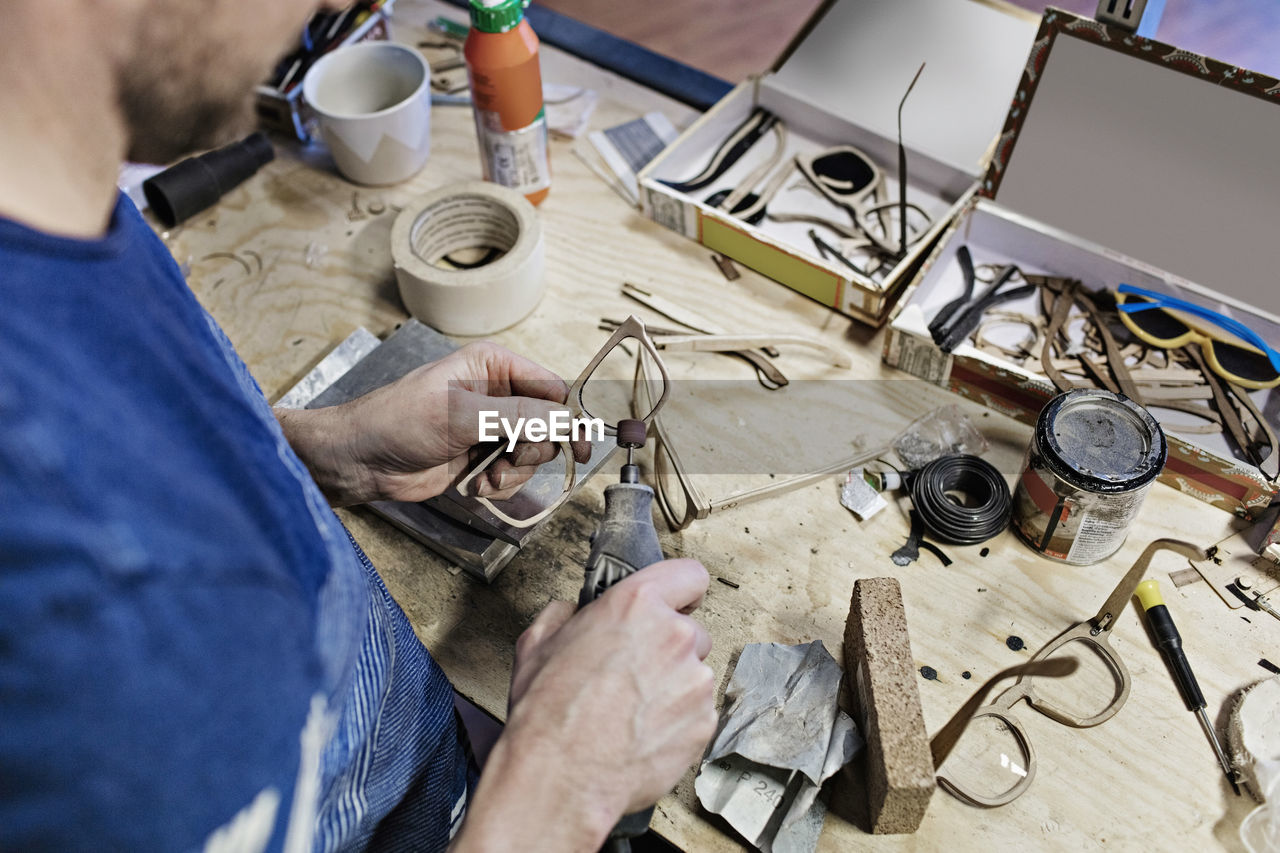 High angle view of owner making eyeglasses with work tool at workshop