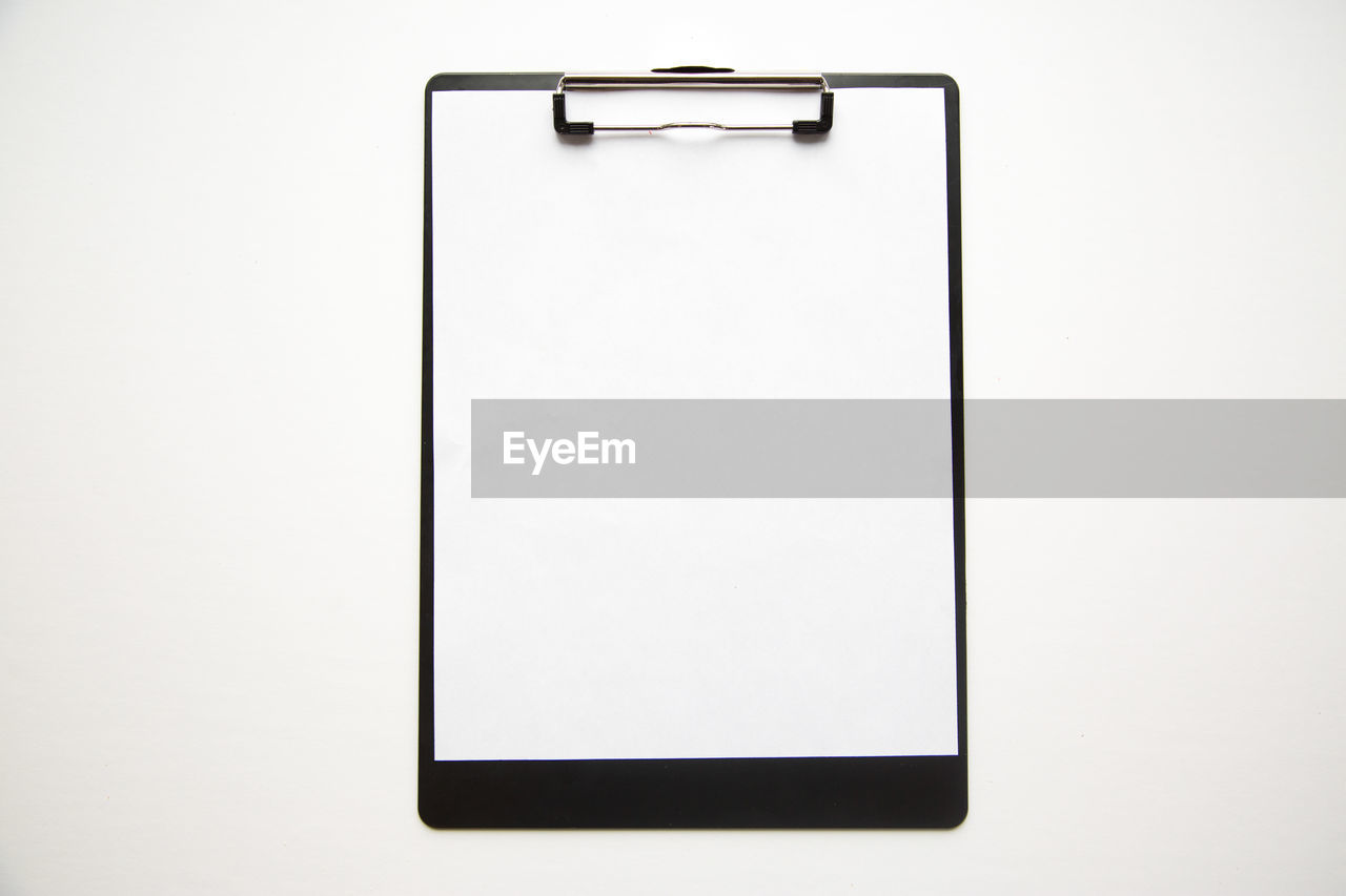 Directly above view of blank clipboard on white background