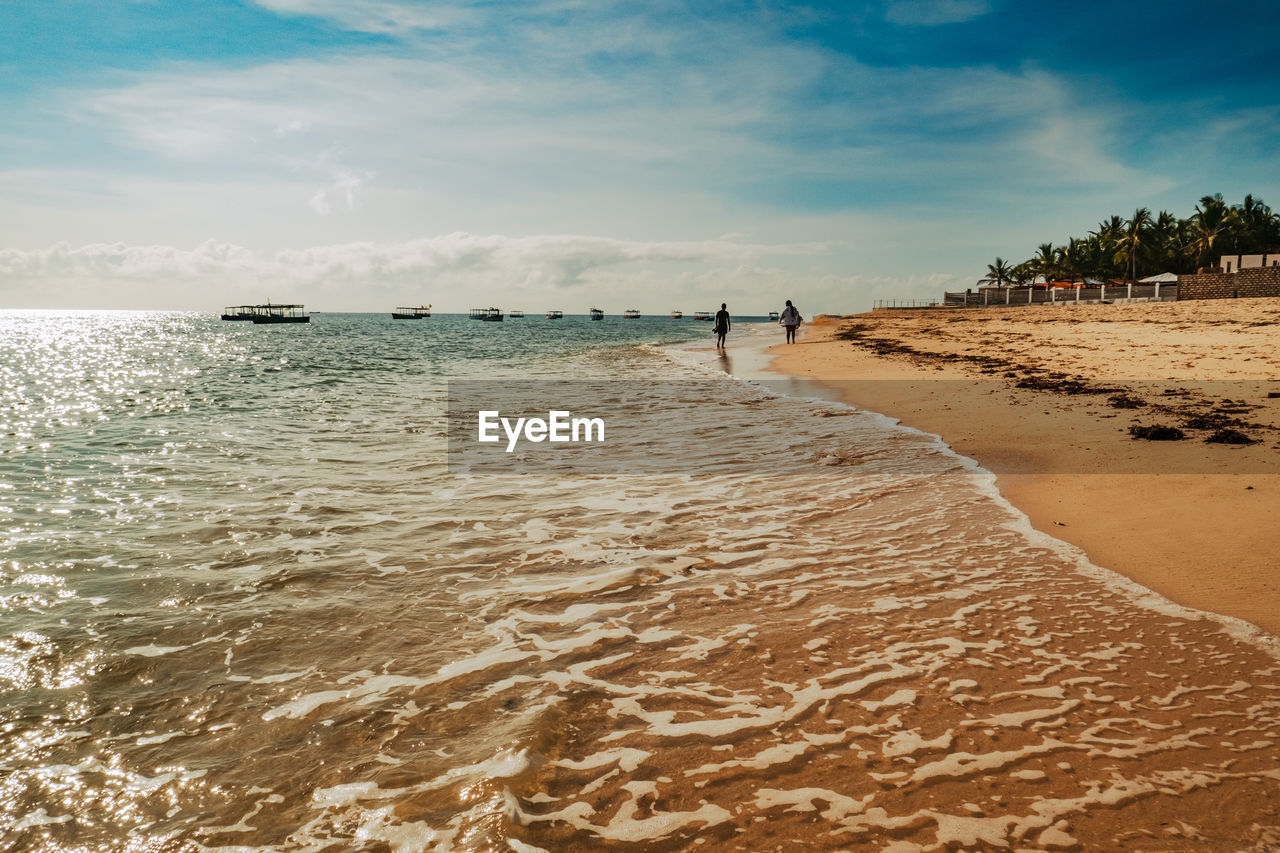 A man and woman walking on the beach at malindi beach at sunset in malindi, kenya