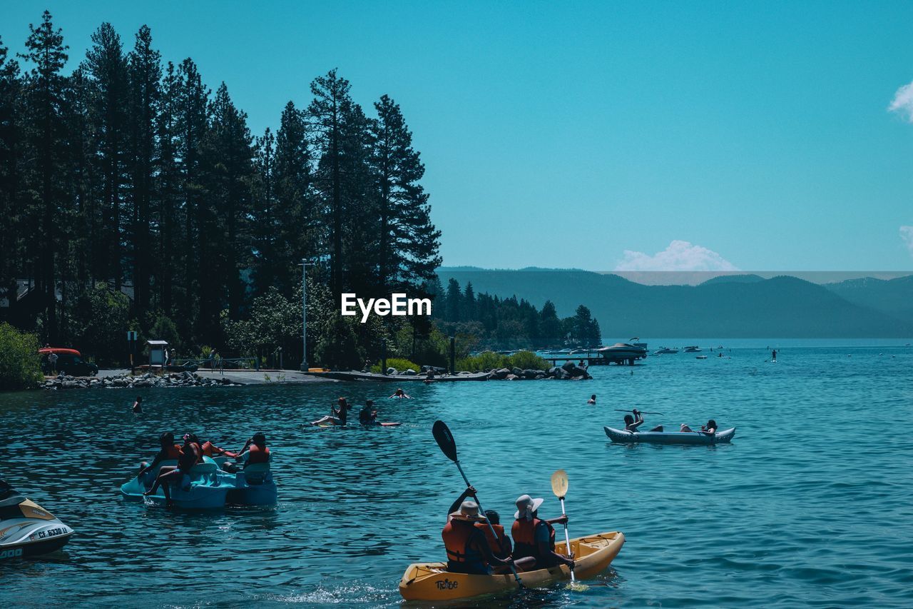 PEOPLE ON BOAT AGAINST LAKE AND MOUNTAINS