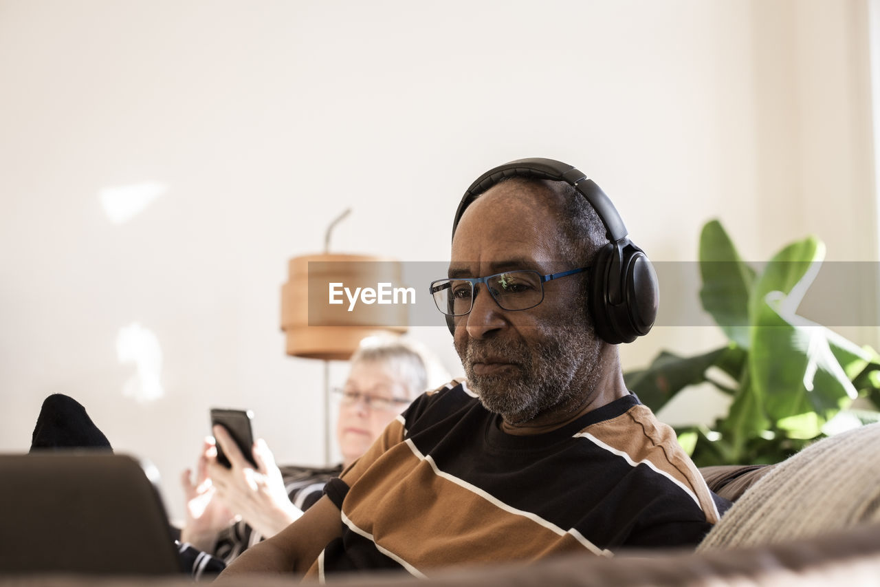 Senior man with headphones using laptop at home