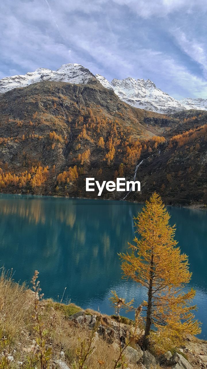 Scenic view of lake by snowcapped mountains against sky