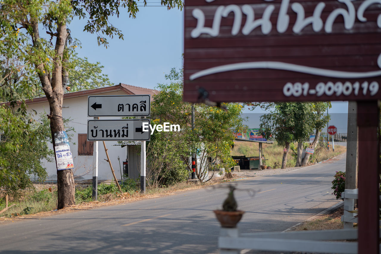 text, sign, communication, neighbourhood, western script, architecture, road, city, town, street, plant, tree, building exterior, nature, road sign, built structure, day, information sign, downtown, lane, no people, urban area, transportation, guidance, symbol, outdoors, travel destinations, footpath, sky, travel, building