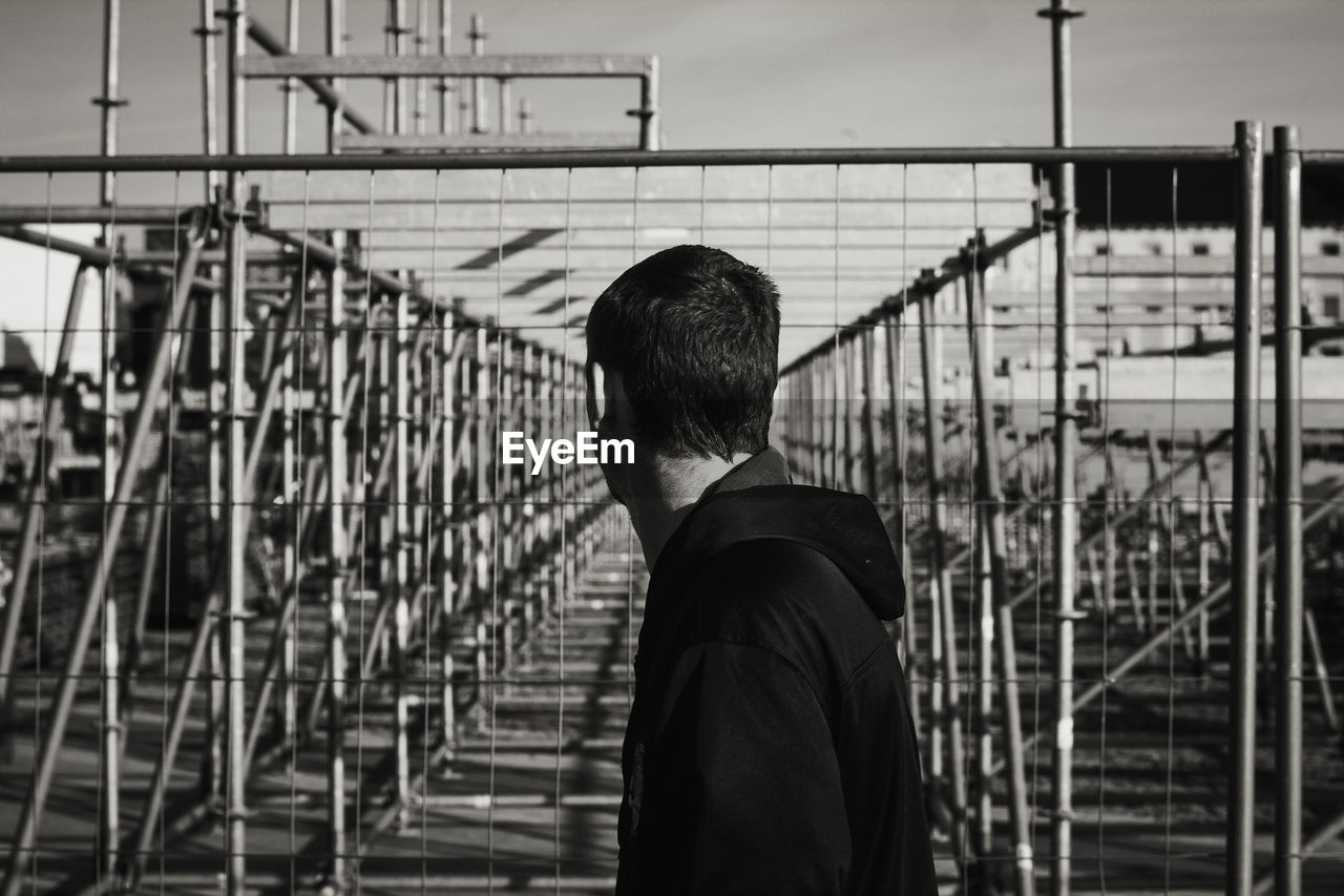 Man standing by railing against sky