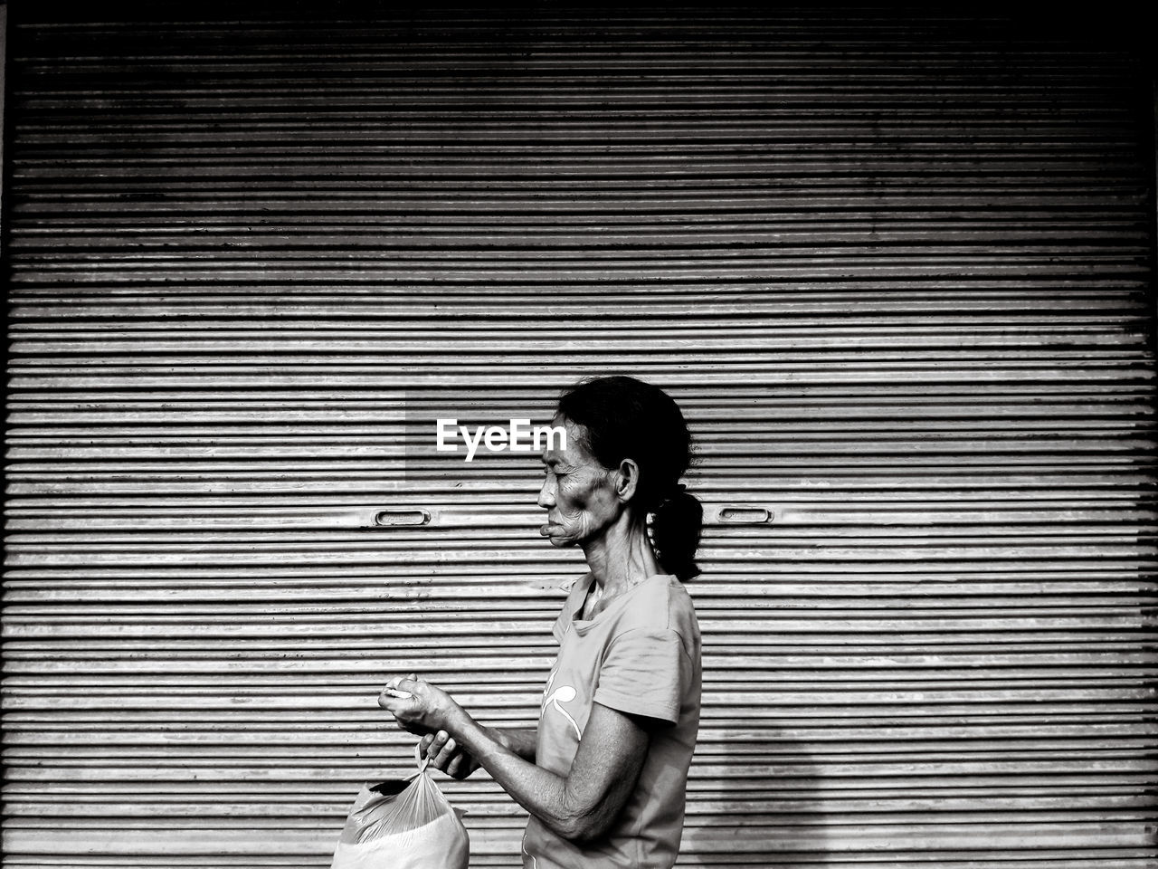 SIDE VIEW OF A YOUNG WOMAN LOOKING AWAY AGAINST WALL