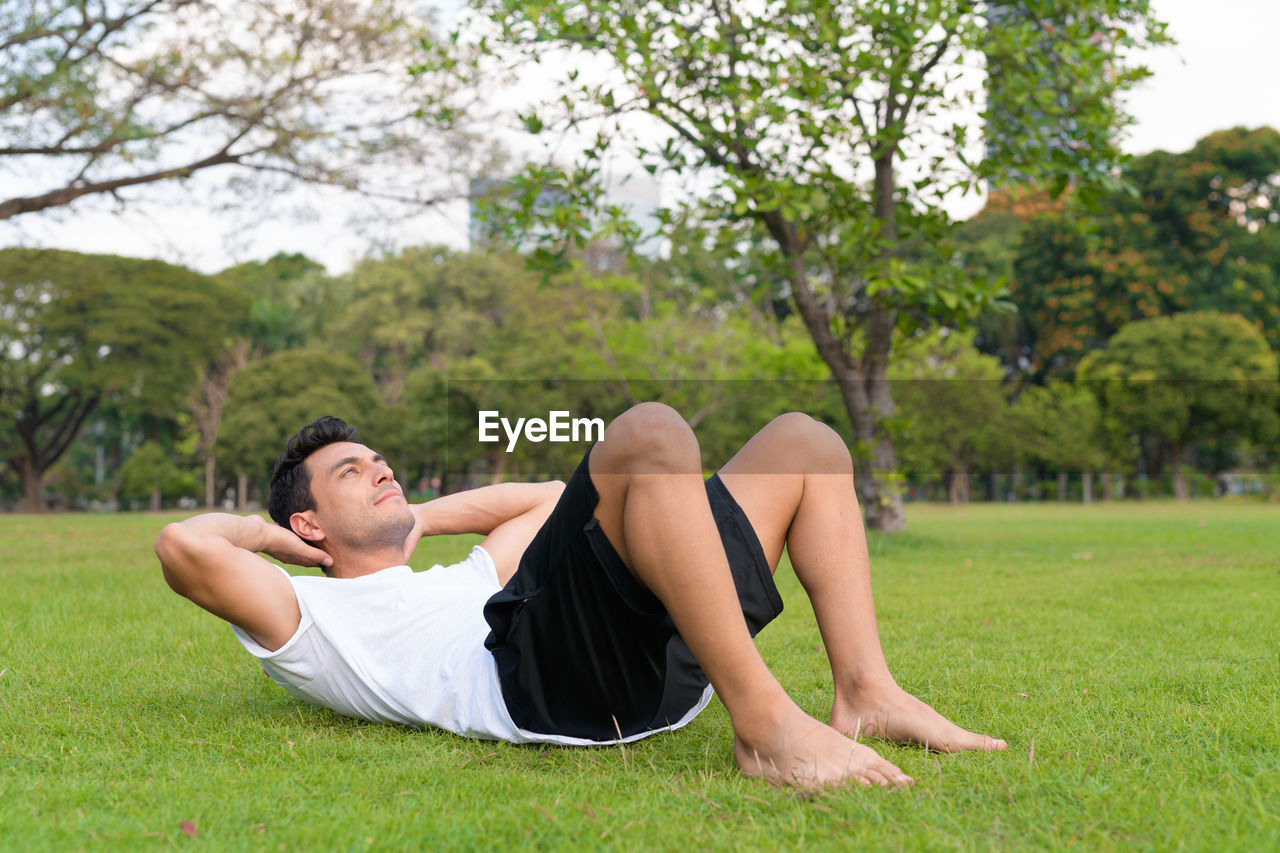 SIDE VIEW OF YOUNG MAN LYING IN GRASS