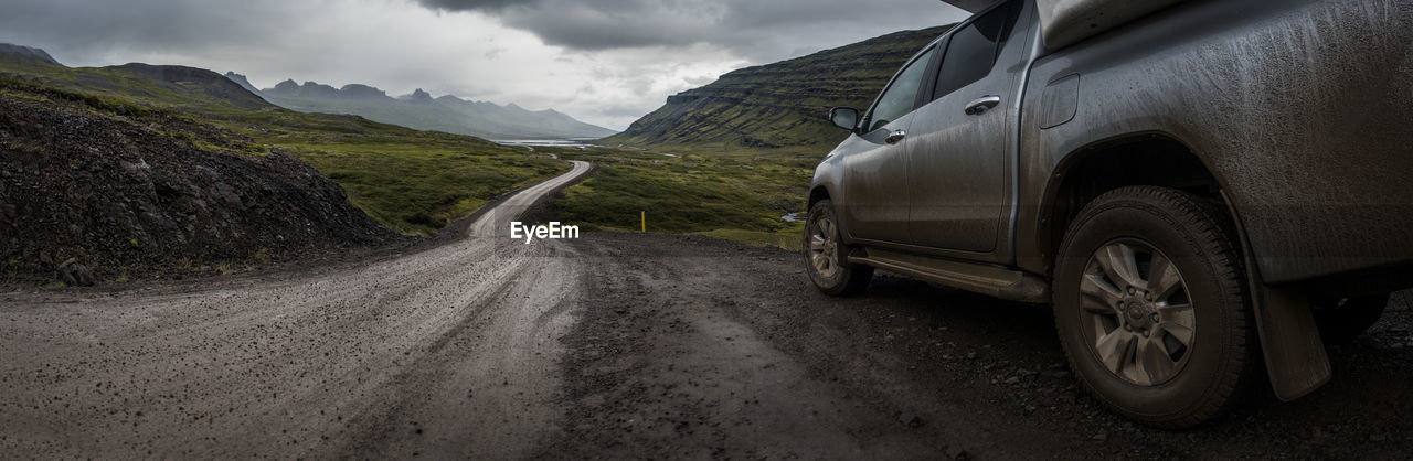 DIRT ROAD BY MOUNTAIN AGAINST SKY