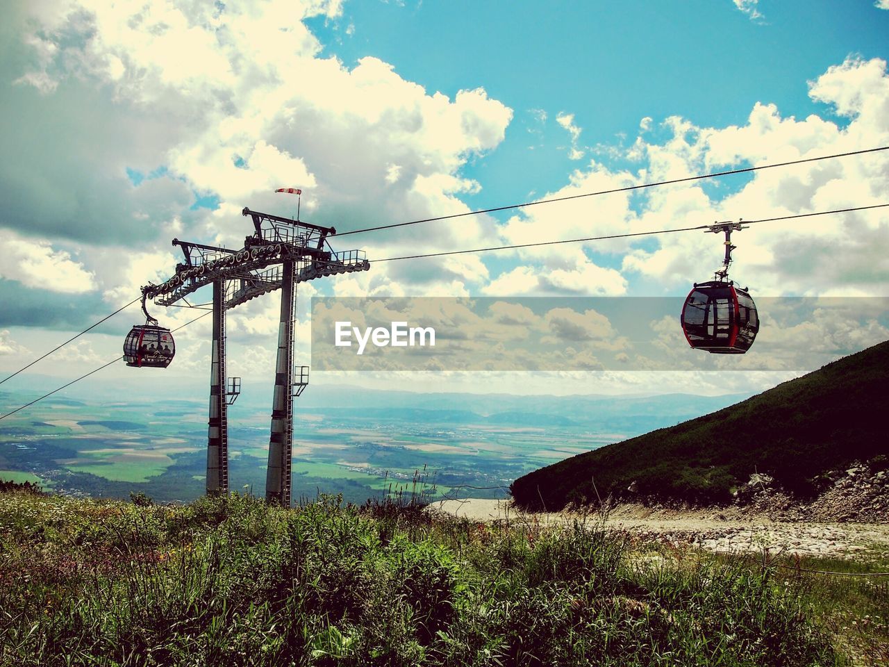 Overhead cable cars on field against sky
