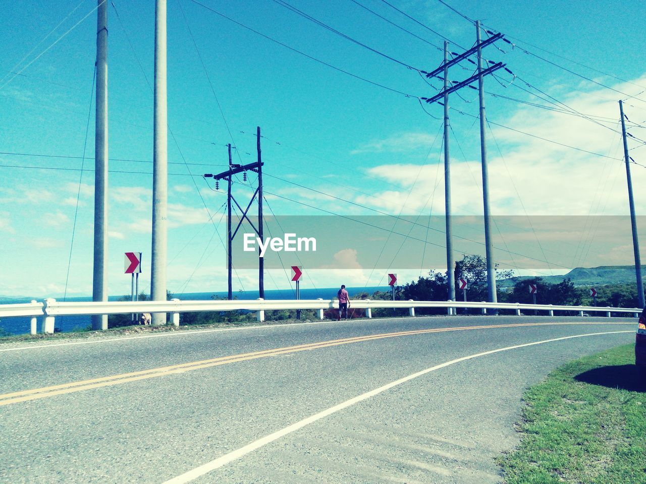 Telephone lines by road against sky