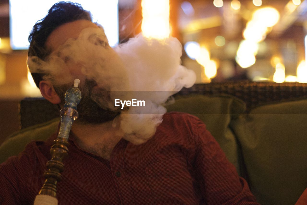 Man smoking hookah while sitting at restaurant