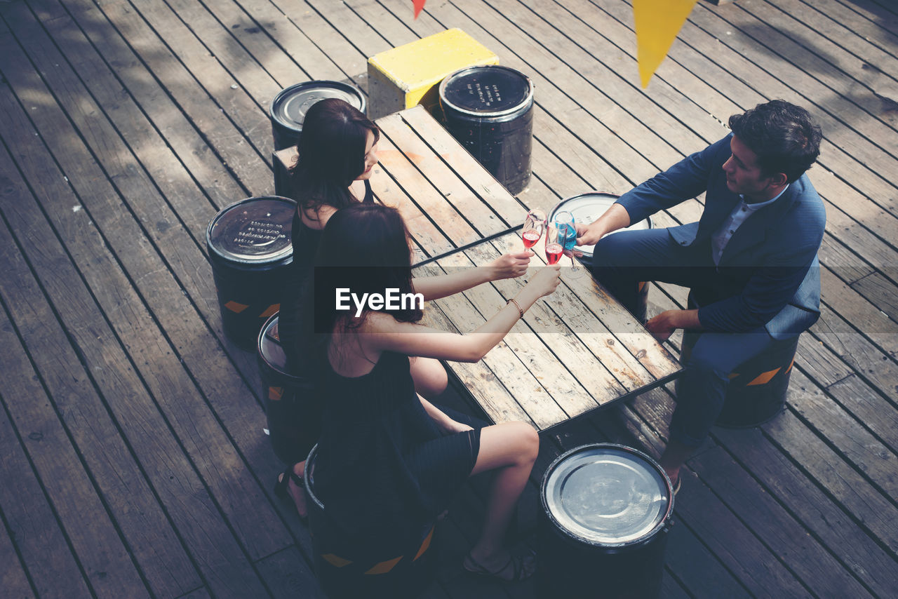 High angle view of friends toasting drinks at bar