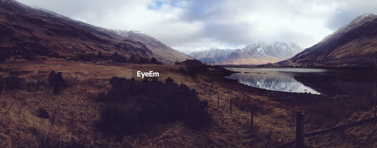 Scenic view of lake with mountains against cloudy sky