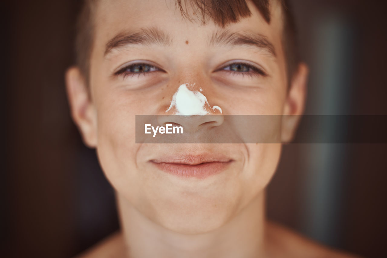 Close-up portrait of boy with suntan lotion on nose