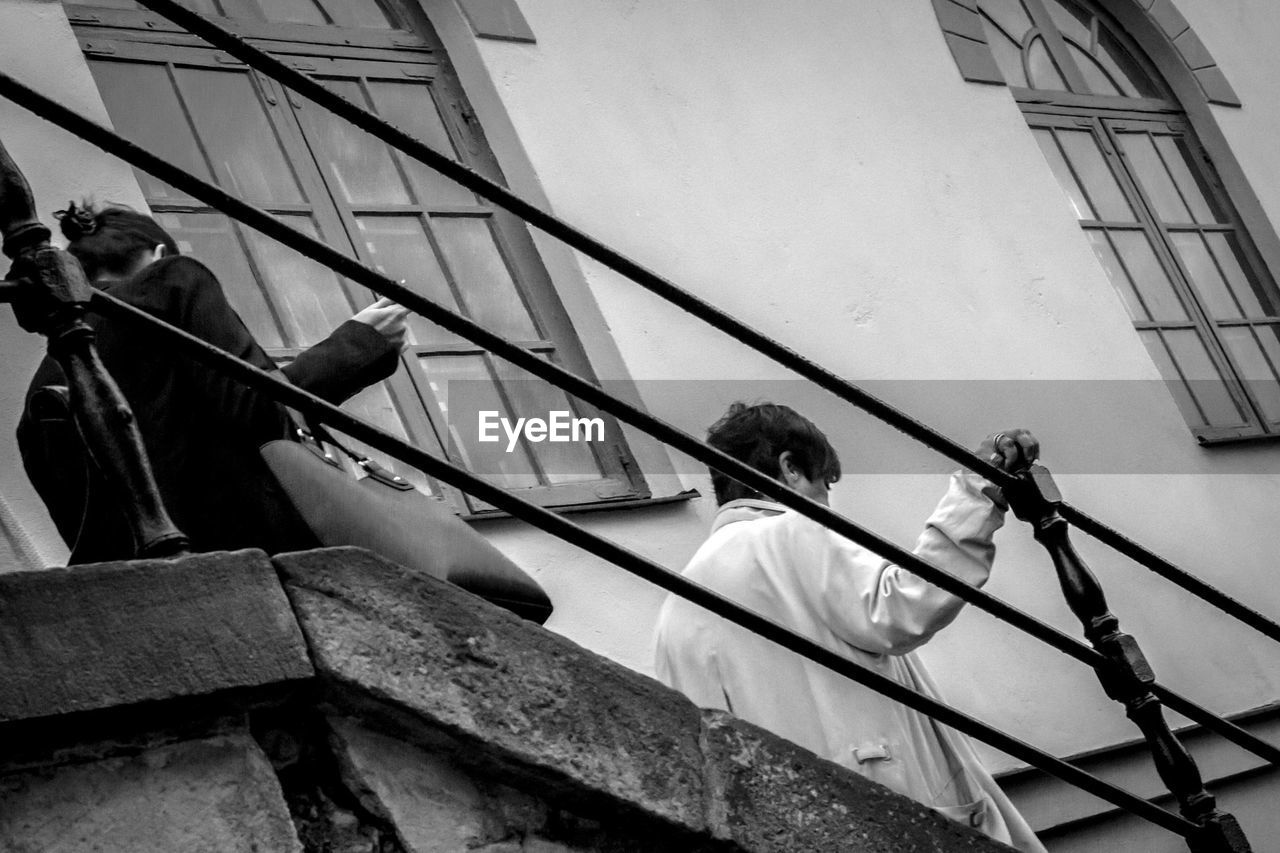 Low angle view of women walking on staircase against building