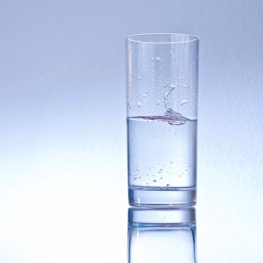 Ice cube falling into glass of water